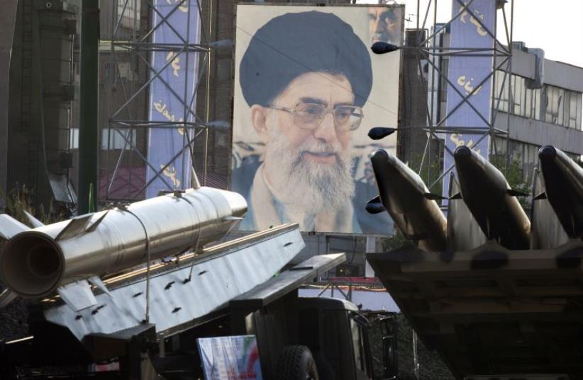Iranian-made Fateh 110 (Conqueror) (L) and Persian Gulf (R) missiles are seen next to a portrait of Iran's Supreme Leader Ayatollah Ali Khamenei at a war exhibition in Tehran (photo credit: REUTERS)