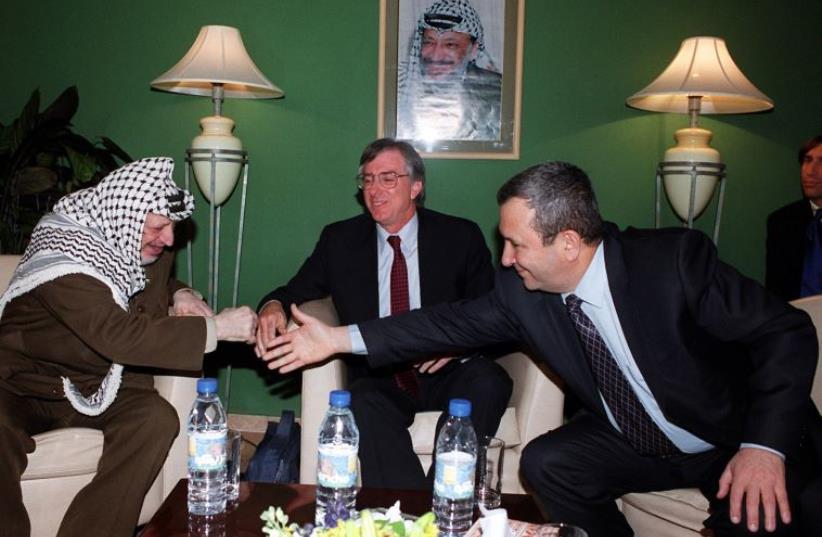 US special envoy Dennis Ross looks on as prime minister Ehud Barak reaches out to shake hands with Palestinian Authority president Yasser Arafat at a meeting in a Ramallah hotel, March 8, 2000 (photo credit: REUTERS)