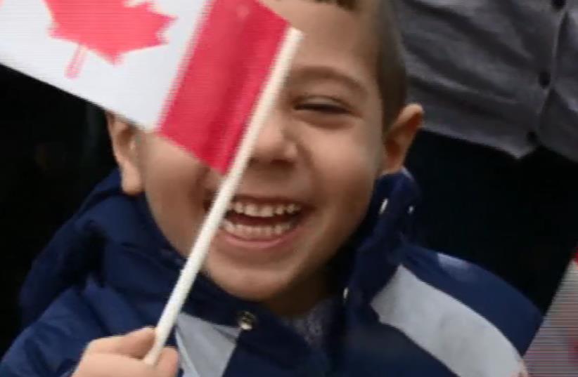 A Syrian refugee boy waves a Canadian flag as he settles into his new home in Canada, December 11, 2015. (photo credit: REUTERS)