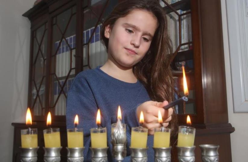 A young girl lights Hannuka candles  (photo credit: MARC ISRAEL SELLEM/THE JERUSALEM POST)
