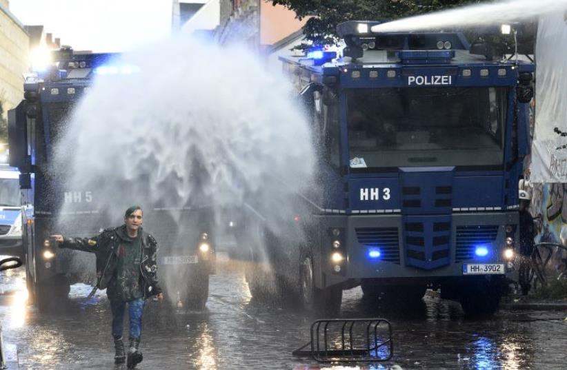A left-wing protestor walks in front of police water cannons during a demonstration against a Nazi demonstration, which was forbidden by authorities, in Hamburg's Schulterblatt street in Schanzenviertel district, September 12, 2015. (photo credit: REUTERS)