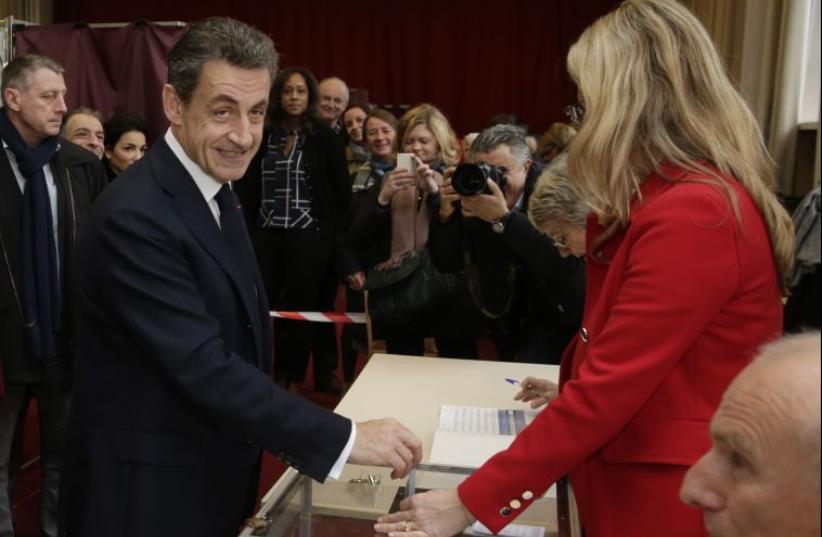 Nicolas Sarkozy (L), former French president and current head of the Les Republicains political party, casts his ballot in the second-round regional elections in Paris, France, December 13, 2015. (photo credit: REUTERS/PHILIPPE WOJAZER)