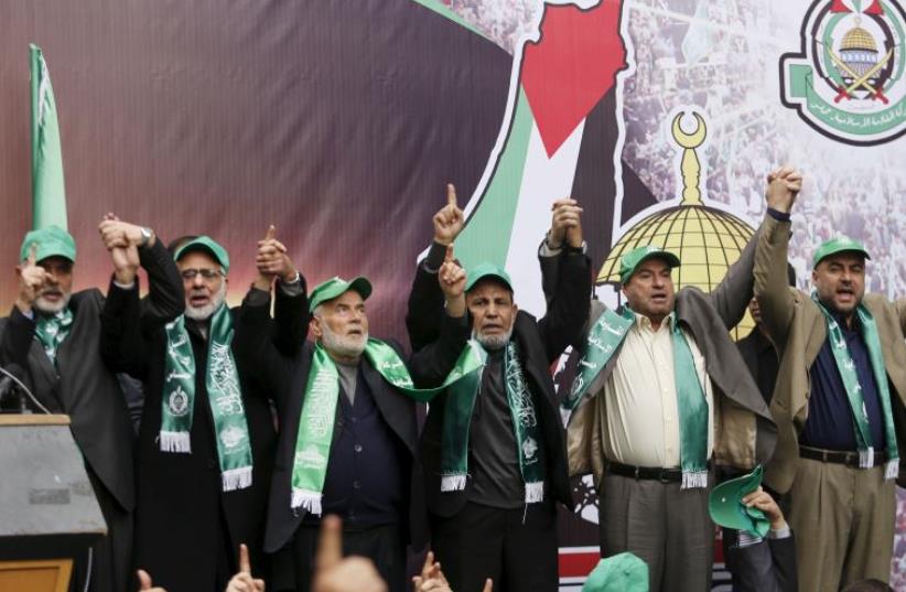 Hamas leaders (top) join hands as they take part in a rally marking the 28th anniversary of Hamas' founding (photo credit: REUTERS)