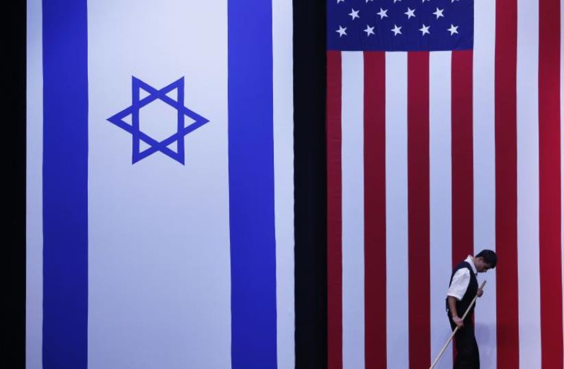 A worker cleans the stage near Israeli and American flags  (photo credit: REUTERS)