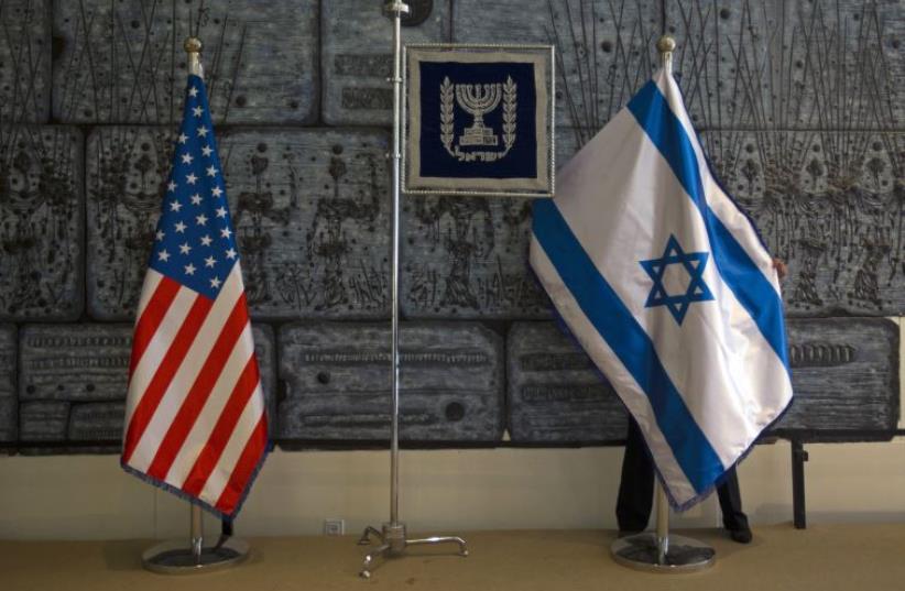 An employee arranges an Israeli national flag next to a U.S. one (photo credit: REUTERS)