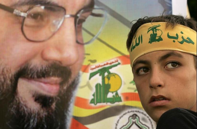 A young Hezbollah follower leans toward an image of the group's leader, Hassan Nasrallah (photo credit: AFP PHOTO)