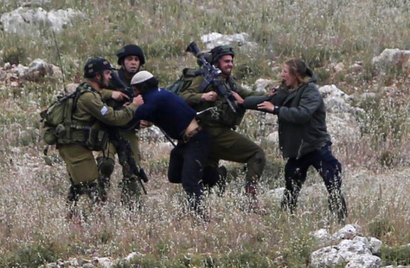 Israeli soldiers detain Jewish settlers during clashes with Palestinians near the West Bank village of Deir Jarir, near Ramallah (photo credit: REUTERS)