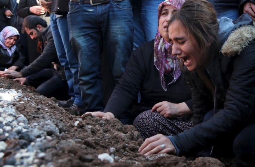 Relatives of Siyar Salman mourn over his grave during a funeral ceremony in the Kurdish dominated southeastern city of Diyarbakir, Turkey (photo credit: REUTERS)