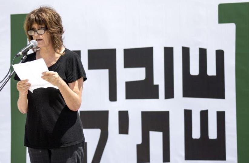 A woman reads testimonies during a gathering in Tel Aviv to commemorate the 10th anniversary of the Israeli NGO "Breaking the Silence" (photo credit: AFP PHOTO)