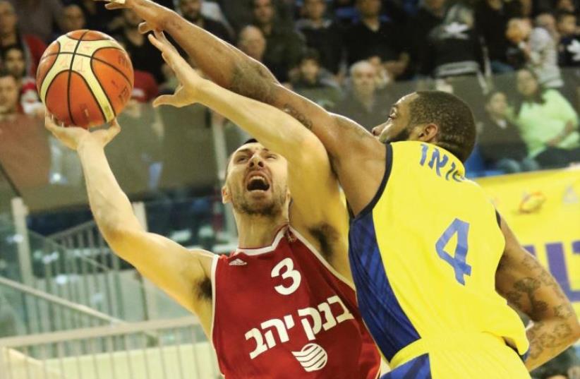 Maccabi Ashdod guard Isaiah Swann (right) blocks Hapoel Jerusalem’s Tony Gaffney (photo credit: DANNY MARON)