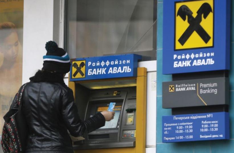 UKRAINIAN woman takes out money from an ATM. Trade with Israel could be boosted, the author argues (photo credit: REUTERS)