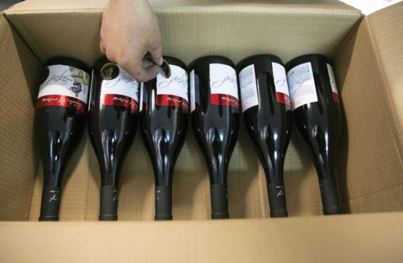 A WORKER places stickers on wine bottles while packaging them for export at Shiloh Wineries, north of Ramallah (photo credit: REUTERS)