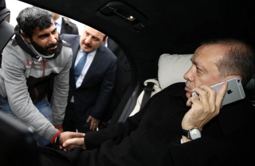 Turkish President Recep Tayyip Erdogan (R) shakes hands with a man who was allegedly about to attempt suicide off the Bosphorus Bridge in Istanbul (photo credit: AFP PHOTO)