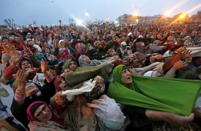Kashmiri Muslim women raise their arms as they pray upon seeing a relic of Prophet Mohammad being displayed during the festival of Eid-e-Milad-ul-Nabi (photo credit: REUTERS)