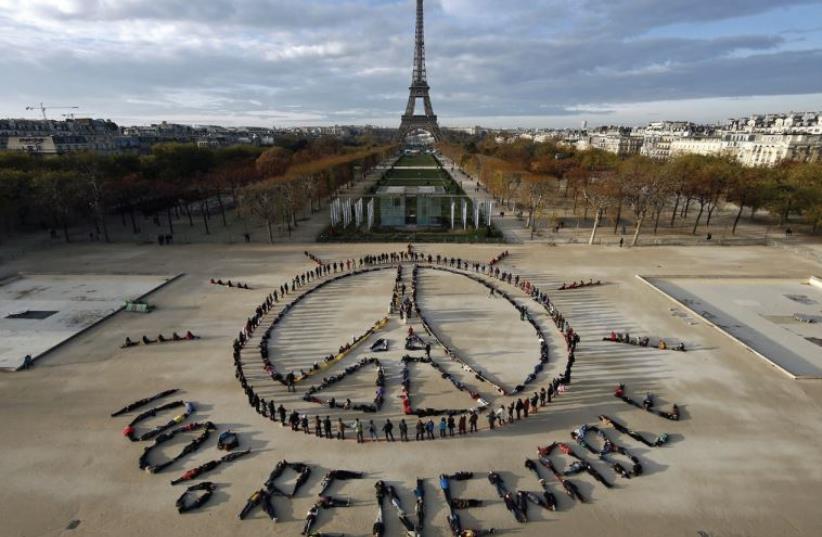 Hundreds of environmentalists arrange their bodies to form a message of hope and peace in front of the Eiffel Tower as the World Climate Change Conference 2015 convened at Le Bourget near the French capital (photo credit: REUTERS)
