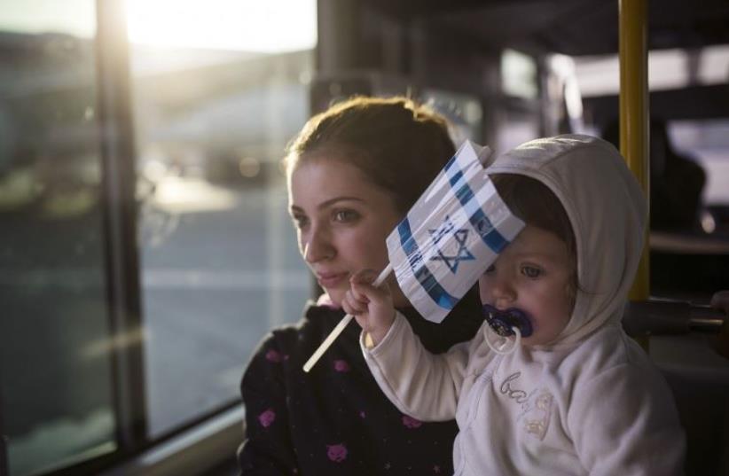 A Jewish immigrant from Ukraine holds her daughter aboard a bus, after arriving at Ben Gurion International Airport near Tel Aviv (photo credit: REUTERS)