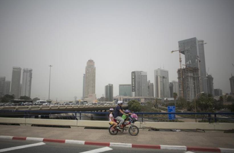 A man rides a bicycle during a sandstorm in Tel Aviv (photo credit: REUTERS)
