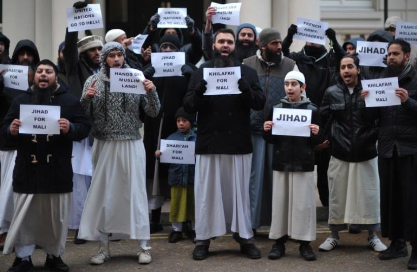 Muslim men and children hold up signs reading "Jihad for Mali", "United Nations go to hell" and calling French President Francois Hollande a "Murderer" as they protest in response to French military action in Mali outside the French embassy in central London on January 12, 2013 (photo credit: CARL COURT/AFP)