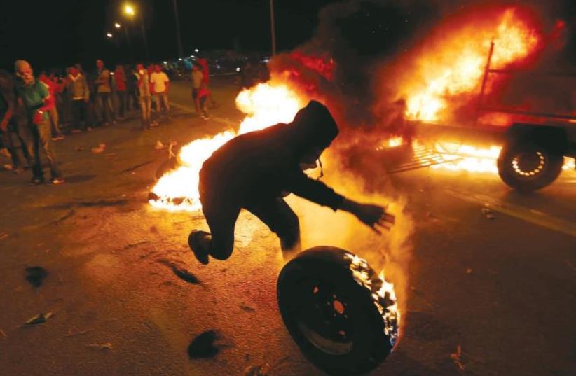 An Israeli Arab rolls a burning tire in a protest in the southern village of Hura in November 2013 (photo credit: REUTERS)