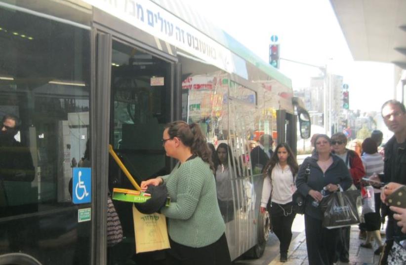 Passengers enter a bus at one of the back doors, helping to speed it on its way (photo credit: SYBIL EHRLICH)