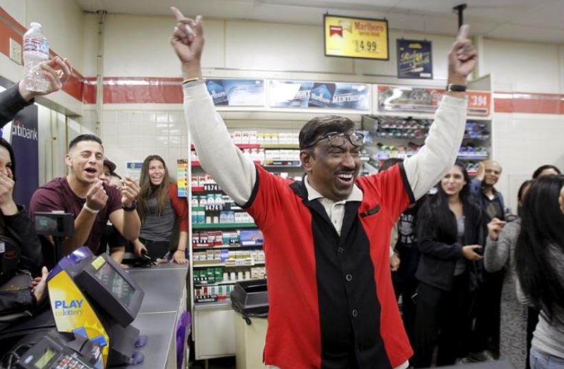 7-Eleven store clerk M. Faroqui celebrates after selling a winning Powerball ticket in Chino Hills, California (photo credit: REUTERS)