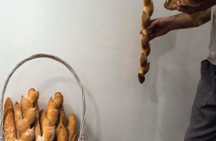 A MAN removes a baguette from a basket at a patisserie in Netanya. Many French Jews have expressed dismay over finding work in Israel and are immigrating elsewhere. (photo credit: REUTERS)