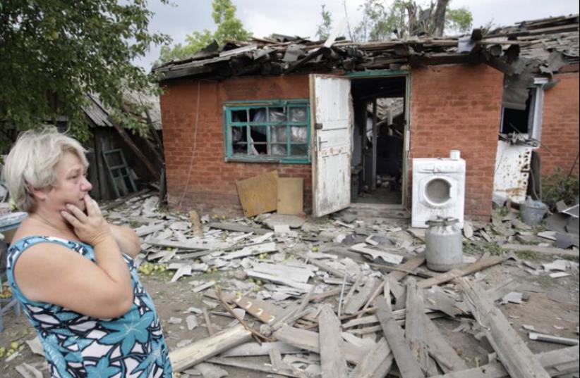 A woman looks with dismay at the ruin of her home, damaged in shelling, on the outskirts of Donetsk, Ukraine, August 16 (photo credit: REUTERS)