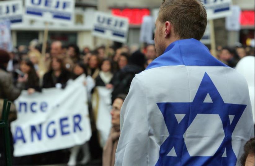 A man with an Israeli flag takes part in a march through Paris (photo credit: REUTERS)