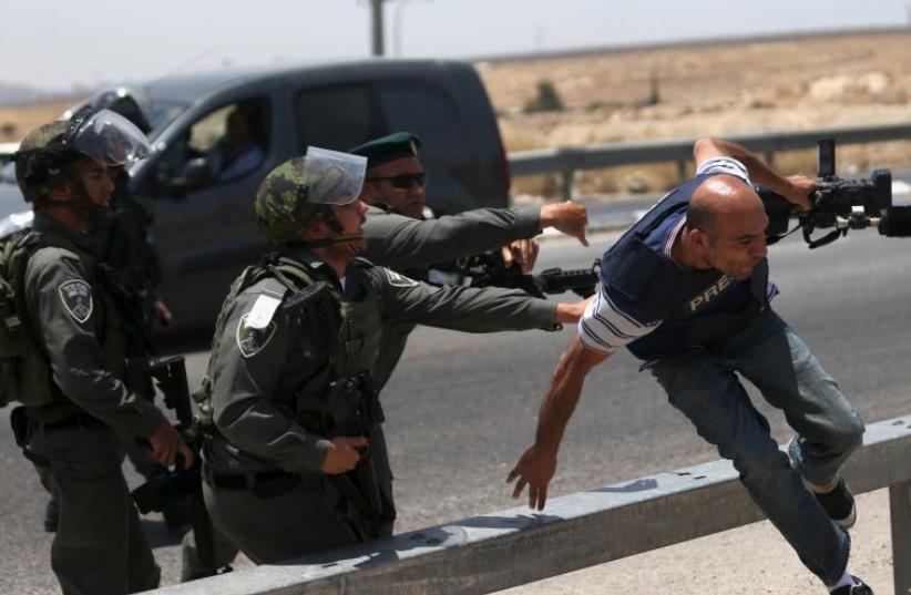 A cameraman runs away from Border Police officers in the West Bank [File] (photo credit: REUTERS)