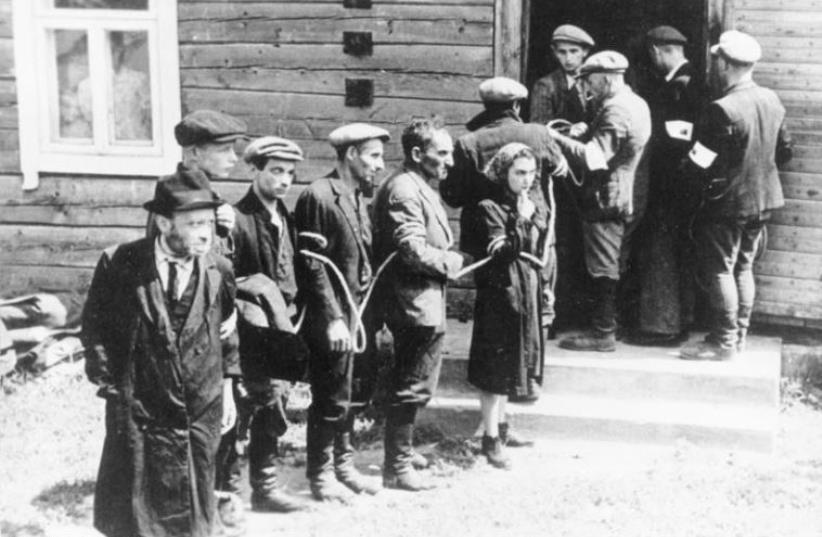 Lithuanian collaborators (with white armbands) arresting Jews in July 1941  (photo credit: WIKIMEDIA COMMONS/GERMAN FEDERAL ARCHIVES)