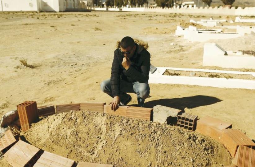 Five years after Tunisia’s Arab Spring, an unemployed graduate, Rabie Gharssali, visits the grave of his friend, Ridha Yahyaoui, who killed himself after being refused a job (photo credit: REUTERS)