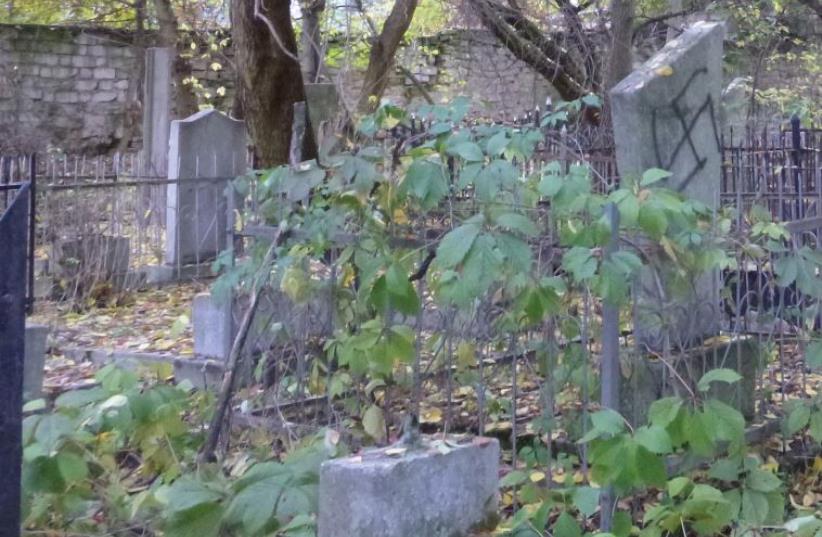 A gravestone at Chisinau’s Jewish cemetery vandalized with a swastika (photo credit: JULIE MASIS)
