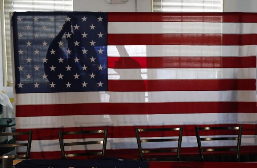 Campaign workers for U.S. Republican presidential candidate and New Jersey Governor Chris Christie put up an American flag before his town hall campaign stop at the Hampton Academy in Hampton, New Hampshire February 7, 2016 (photo credit: REUTERS)