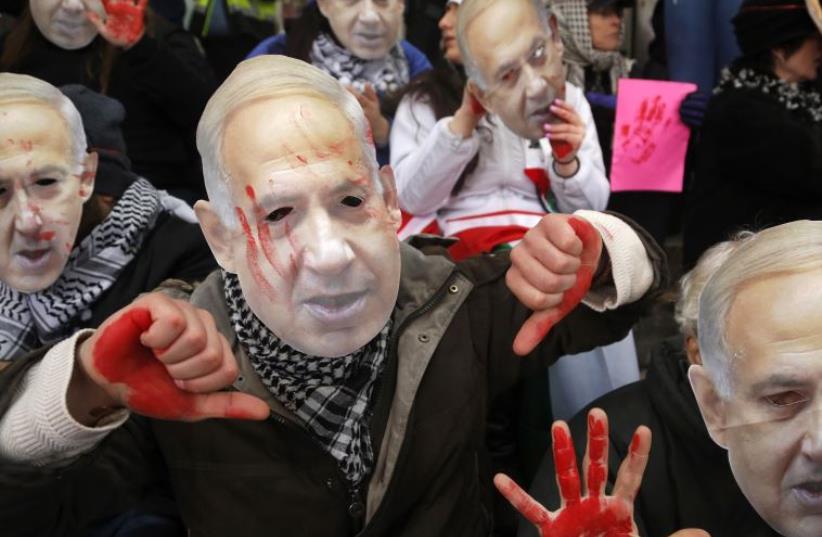 Anti-Israel demonstrators led by the protest group Code Pink wear masks of Prime Benjamin Netanyahu as they sit at the entrance to the AIPAC policy conference in Washington (photo credit: REUTERS)