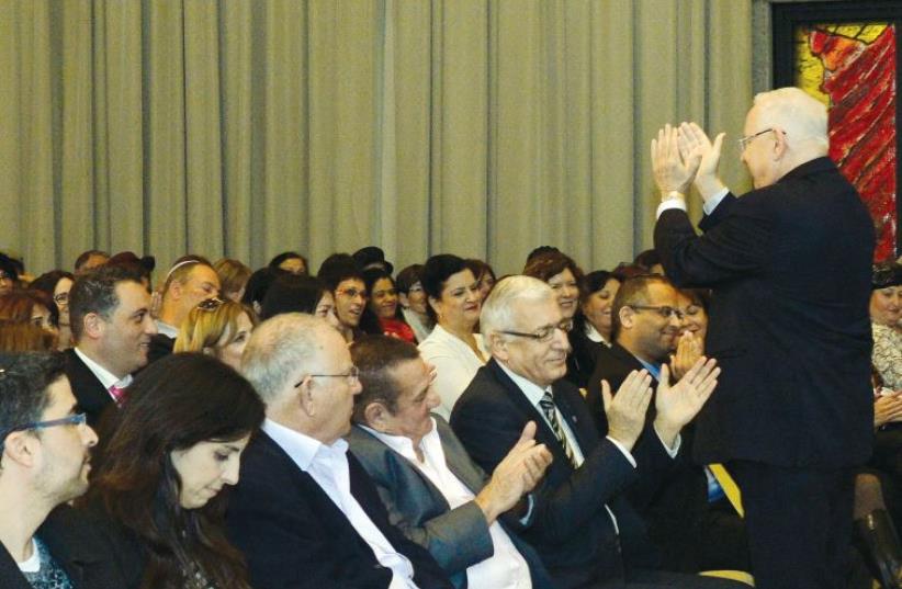 President Rivlin and several victims of terror (front row) applaud the dedication of the NII’s social workers (photo credit: HAIM ZACH/GPO)