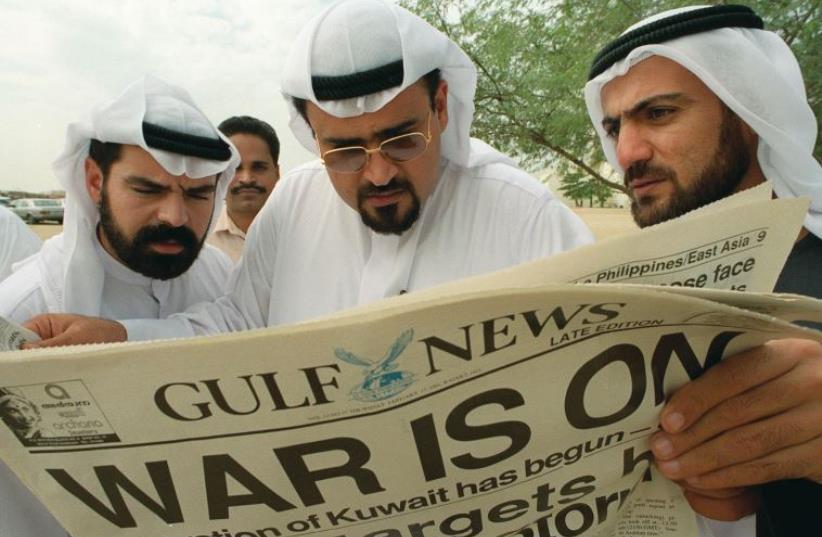 Kuwaiti exiles read a local newspaper announcing the start of the Gulf War in Dubai on January 17, 1991 (photo credit: REUTERS)