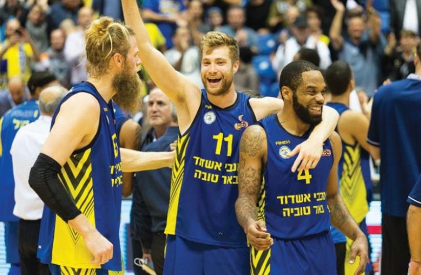 Maccabi Ashdod’s Jonathan Skjoldebrand (left), Willy Workman (center) and Isaiah Swann celebrate after their team’s 84-82 double-overtime win over Maccabi Rishon Lezion in the State Cup semifinals at Yad Eliyahu Arena last night. (photo credit: ODED KARNI/ISRAEL BASKETBALL ASSOCIATION))