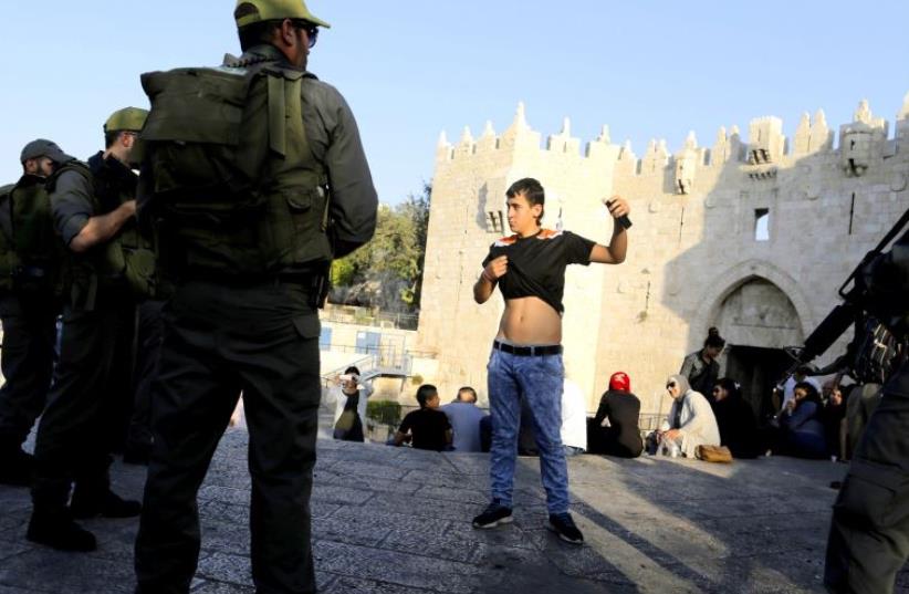 Border Policemen check a Palestinian youth at the Damascus Gate, the scene of multiple terror attacks in Jerusalem’s Old City. (photo credit: REUTERS)