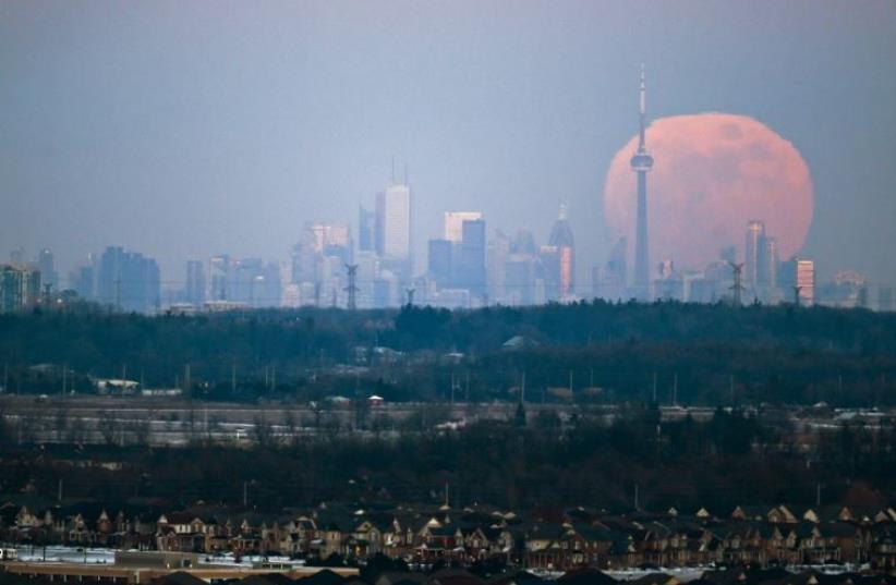 The moon rises over the Toronto city skyline as seen from Milton, Ontario (photo credit: REUTERS)