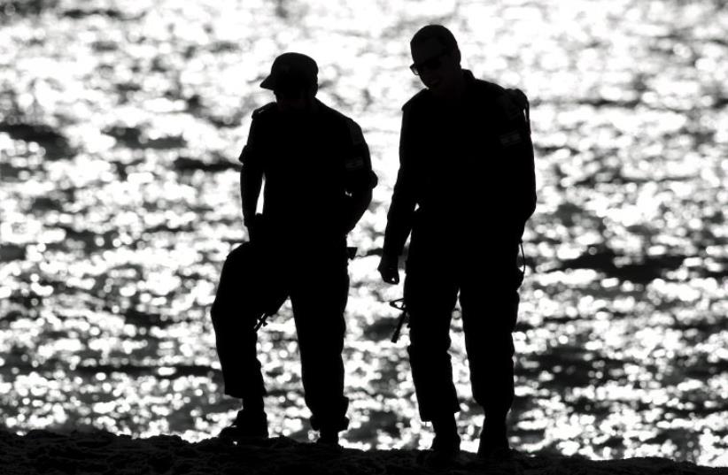 Off duty IDF soldiers are silhouetted as they walk on the shore of the Mediterranean sea   (photo credit: REUTERS)
