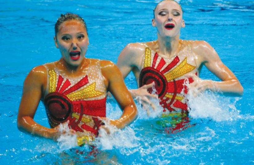 Yulia Kim and Anastasiya Ruzmetova of Uzbekistan perform in the synchronized swimming duet technical preliminary round at the Aquatics World Championships in Kazan, Russia (photo credit: REUTERS)