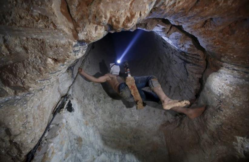 A Palestinian worker is lowered on a rope into a smuggling tunnel that was flooded by Egyptian security forces (photo credit: REUTERS)