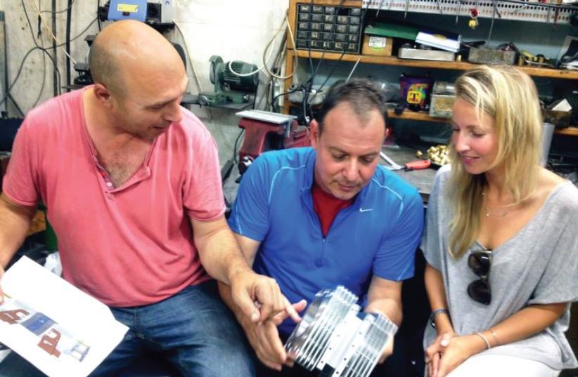 Shaul Yaakoby, in his lab, in the process of building the first version of the Aquarius engine, shows it to Gal Fridman and Maya Gonik (photo credit: COURTESY AQUARIUS)