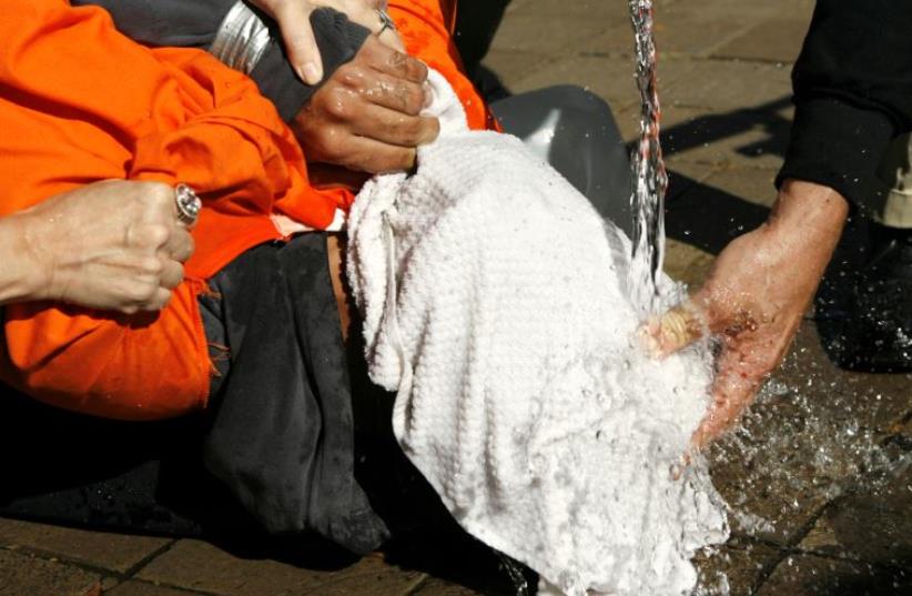 Demonstrator Maboud Ebrahimzadeh is held down during a simulation of waterboarding outside the Justice Department in Washington (photo credit: REUTERS)