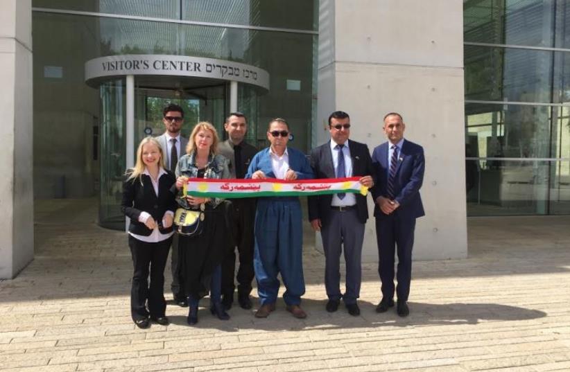 Some of the members of the Yazidi and Kurdish delegation at Yad Vashem on Sunday unfurl a Kurdish flag at the entrance. They were accompanied by Dr Susanna Kokkonen, director of the Christian Friends of Yad Vahsem (far left) and Lisa Miara (third on left), founder of the Spring of Hope Foundation. (photo credit: SETH J. FRANTZMAN)