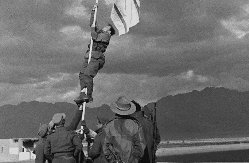 Raising the ink-drawn flag in Eilat. Picture by Micha Perry, an officer in the Negev Brigade, March 10, 1949 (photo credit: Wikimedia Commons)