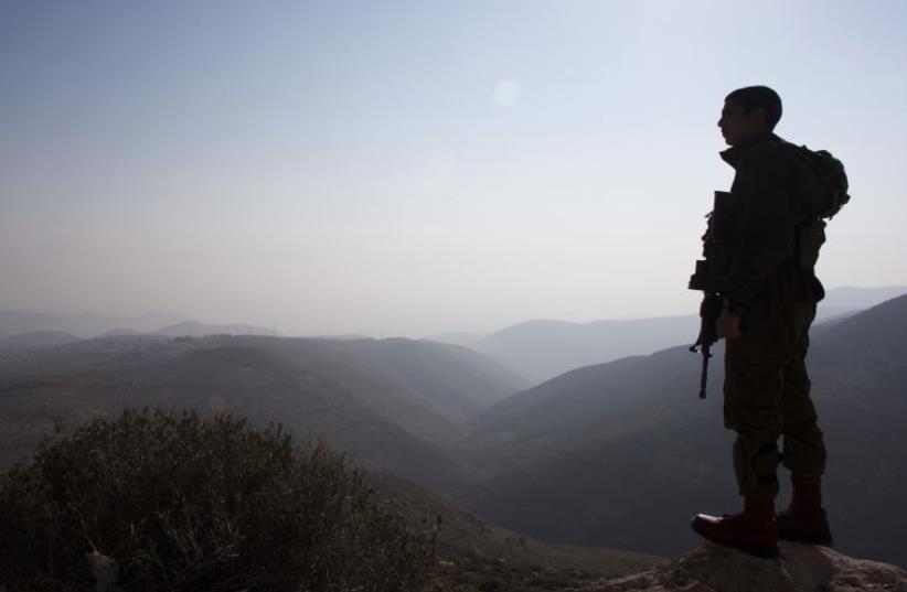 An IDF soldier stands guard during a tour made by Israeli parliament members in the Jordan Valley [File] (photo credit: REUTERS)