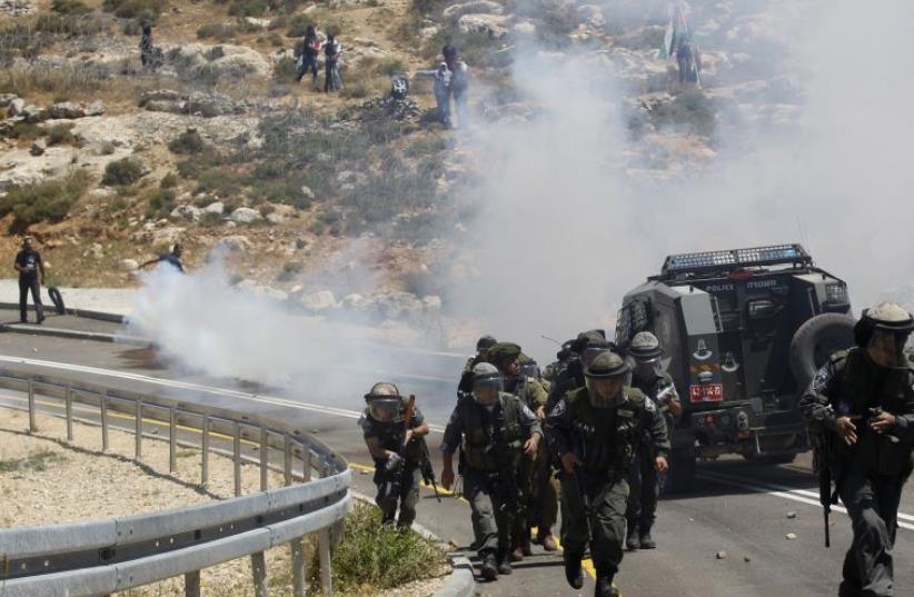 Israeli soldiers run during clashes with Palestinian protesters at a protest marking the 66th anniversary of Nakba, in the West Bank village of El Walaja near Bethlehem May 15, 2014 (photo credit: REUTERS)