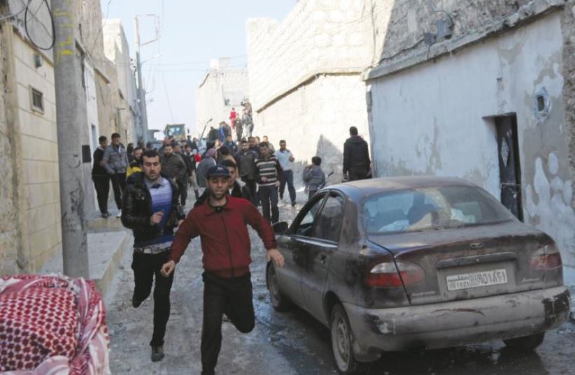 Residents run along a street after an air strike by a fighter jet loyal to Syrian President Bashar Assad in Aleppo’s al-Marja district in December 2012 (photo credit: REUTERS)