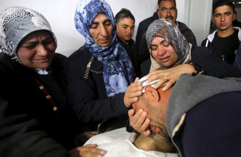 The brother and the mother (C) of Palestinian Qasim Jaber, 31, who the Israeli military said was shot dead by the Israeli army after he carried out an attack on Israelis, mourn as they look at his body in Hebron (photo credit: REUTERS)